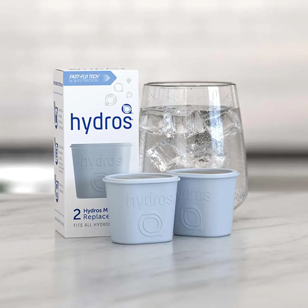 Hydros replacement water filters with their packaging beside a glass of ice water